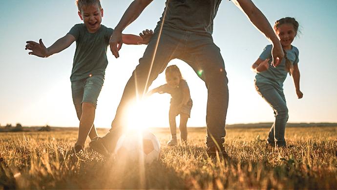 Produkter för hygien och utvärtesvård | Trikem Familj som spelar fotboll på en äng